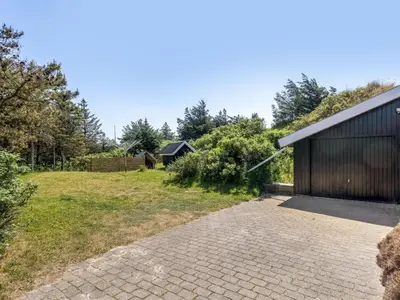 a contemporary house with a black facade and a brick driveway at Holiday Home Letje - 500m from the sea by Interhome in Løkken