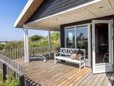 a porch with a bench on a deck at Holiday Home Letje - 500m from the sea by Interhome in Løkken