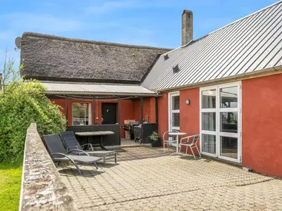 a red house with a patio with chairs and a table at Holiday Home Edvardsine - 20m to the fjord by Interhome in Vestervig