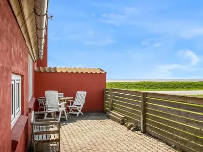 a patio with two chairs and a table on the side of a house at Holiday Home Edvardsine - 20m to the fjord by Interhome in Vestervig