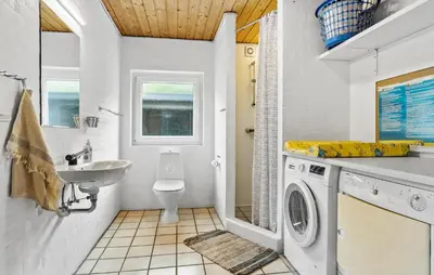 a bathroom with a washing machine and a sink at Cozy Home In Spøttrup With Sauna in Spottrup