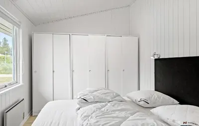 a bedroom with a bed with white sheets and pillows at 4 Bedroom Beautiful Home In Blokhus in Blokhus