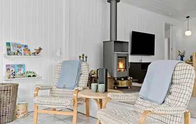a living room with two chairs and a fire place at 4 Bedroom Beautiful Home In Blokhus in Blokhus