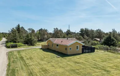 a small house on a grass field next to a road at Lovely Home In Thisted With Kitchen in Thisted