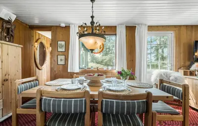 a dining room with a table and chairs and a chandelier at Røgegård Hjortehytten in Fjerritslev