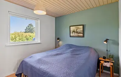 a bedroom with a blue bed and a window at Pet Friendly Home In Farsø With Kitchen in Farsø