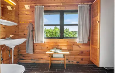 a bathroom with wooden walls and a sink and a window at 2 Bedroom Lovely Home In Saltum in Saltum