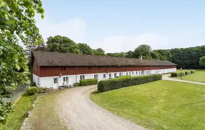 a large red and white barn with a dirt road at Lejl 1 in Brovst