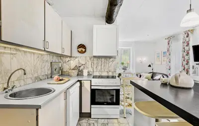 a white kitchen with a sink and a stove at Lejl 1 in Brovst
