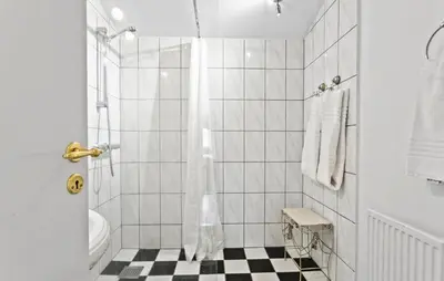 a white bathroom with a black and white checkered floor at Hus 2 in Brovst