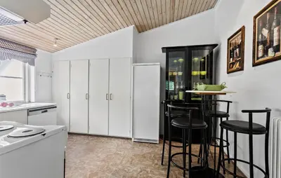 a kitchen with white cabinets and bar stools at Hus 2 in Brovst