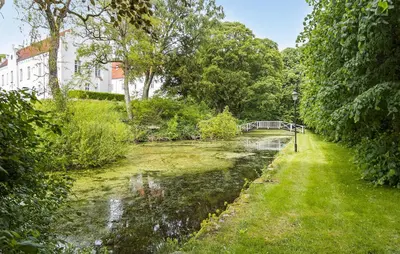 a river with a bridge in the middle of a yard at Lejl 7 in Brovst