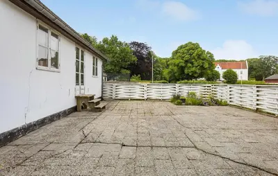 a white building with a bench next to a fence at Lejl 7 in Brovst