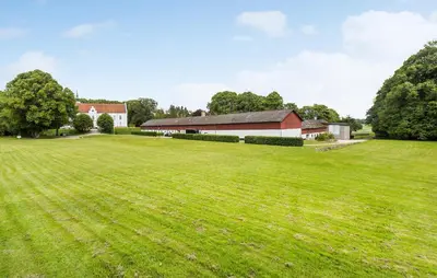 a large field with a barn and a large building at Lejl 2 in Brovst