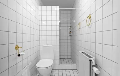 a white tiled bathroom with a toilet and a shower at Lejl 2 in Brovst