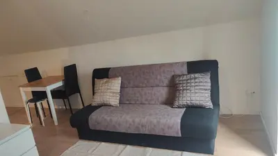 a couch sitting in a living room with a table at Billig overnatning tæt på badestrand og jesperhus in Roslev