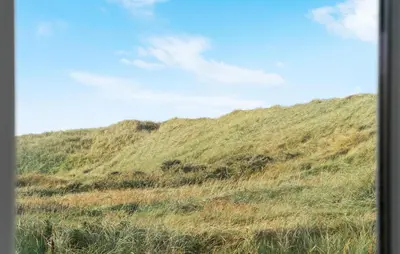 a grassy hill with a blue sky in the background at Nice Home In Harboøre With Kitchen in Harboør