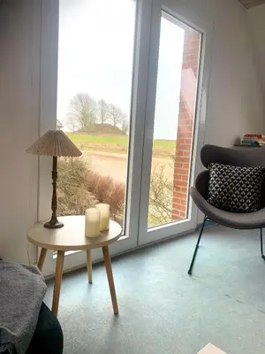 a living room with a table and a chair and a window at Kongshøjgaard in Farsø