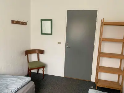 a room with a bed and a chair and a door at Kongshøjgaard in Farsø