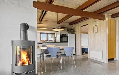 a fireplace in a living room with a table and chairs at Cozy Home In Harboøre With Wifi in Harboør
