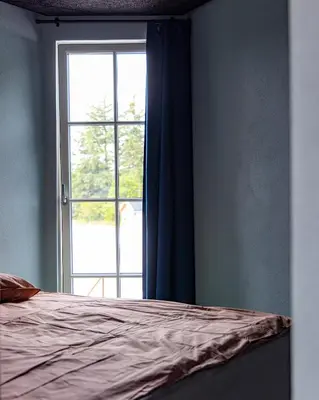 a bedroom with a bed and a window at Fun Art Blokhus in Blokhus