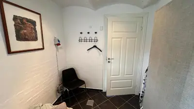 a hallway with a black chair and a white door at Staudeengen et dejlig sted med fred og ro in Ålestrup