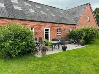 a brick house with a table and chairs in the yard at Staudeengen et dejlig sted med fred og ro in Ålestrup