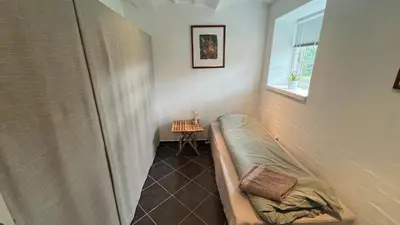 a small room with a bed and a window at Staudeengen et dejlig sted med fred og ro in Ålestrup