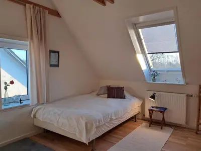 a bedroom with a bed and two windows at Hytten in Frøstrup