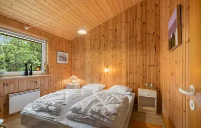 a bedroom with a bed in a wooden wall at Stunning Home In Brovst With Sauna in Brovst