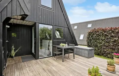 a black house with a wooden deck with a table at Nice Home In Farsø With Kitchen in Farsø