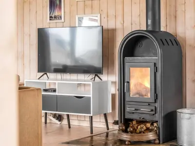 a wood stove in a living room with a television at Holiday Home Hughe - 200m from the sea by Interhome in Frøstrup