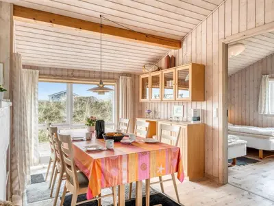 a kitchen and dining room with a table and chairs at Holiday Home Hughe - 200m from the sea by Interhome in Frøstrup