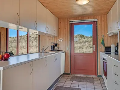 a kitchen with white cabinets and a red door at Holiday Home Frandsine - 1-2km from the sea by Interhome in Thisted