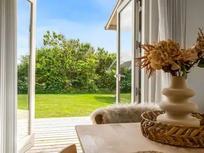 a vase of flowers on a table in front of a window at Holiday Home Gedda - from the sea by Interhome in Vestervig