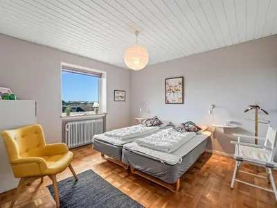 a bedroom with a bed and a chair and a window at Holiday Home Hilppa - 400m from the sea by Interhome in Harboør