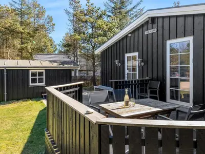 a backyard with a wooden deck and a table at Holiday Home Hellena - 700m from the sea by Interhome in Torsted