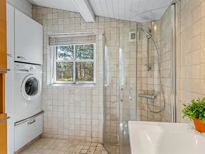 a bathroom with a shower and a washing machine at Holiday Home Hellena - 700m from the sea by Interhome in Torsted
