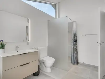a white bathroom with a toilet and a shower at Holiday Home Helga - 650m from the sea by Interhome in Torsted