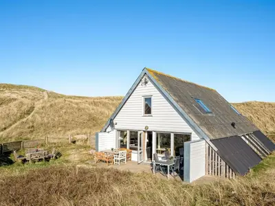 a small white house on the side of a hill at Holiday Home Kurt - 75m from the sea by Interhome in Harboør