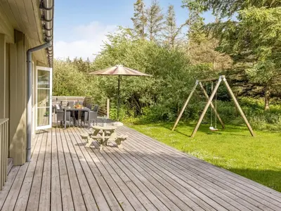 a wooden deck with a picnic table and a swing at Holiday Home Yngve - 1-2km from the sea by Interhome in Løkken