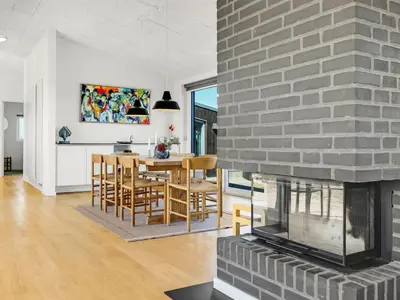 a kitchen and dining room with a brick fireplace at Holiday Home Carit - 450m from the sea by Interhome in Løkken