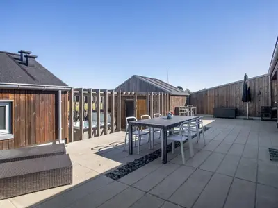 a patio with a table and chairs on a deck at Holiday Home Carit - 450m from the sea by Interhome in Løkken