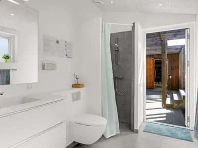 a white bathroom with a shower and a toilet at Holiday Home Carit - 450m from the sea by Interhome in Løkken
