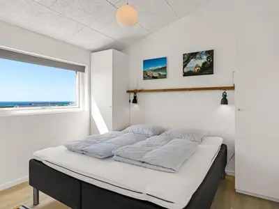 a bed in a room with a large window at Holiday Home Carit - 450m from the sea by Interhome in Løkken