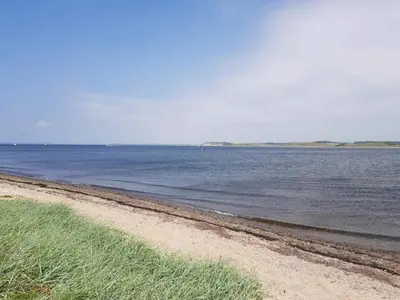 a beach with the ocean and grass on it at 5 person holiday home in Roslev-By Traum in Roslev