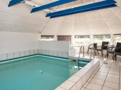 a large swimming pool with chairs and a table at 4 star holiday home in Harboøre in Harboør