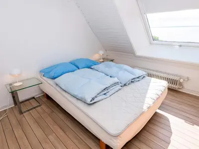 a bed with blue pillows in a room with a window at Family Fun with Fjord View - By Traum Ferienwohnungen in Thyholm
