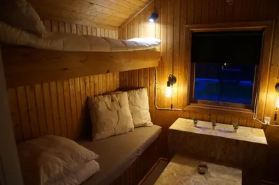 a small room with a bed and a sink in a cabin at Hedelandets Camping in Sevel
