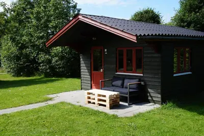 a small black shed with a chair and a bench at Hedelandets Camping in Sevel